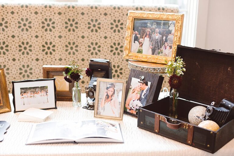 A table decorated with wedding photographs, old cameras, and a vintage suitcase.