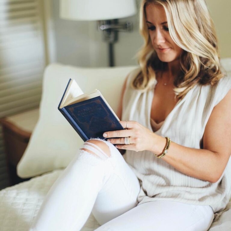 A woman sits on a couch, reading a book.