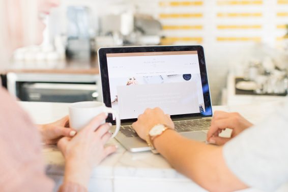 Close up of two people looking at a website on their laptop.