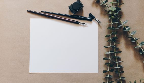 a blank piece of paper on a desk with a pen