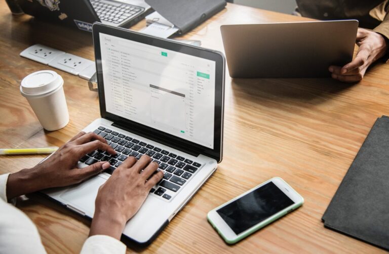 laptops on a desk with people working at them