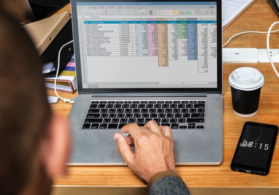 Over the shoulder image of a man typing out his business plan in a spreadsheet.