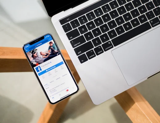 photographer on a phone next to a laptop with facebook ads