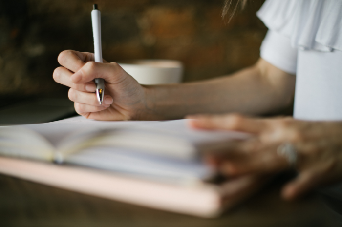 a woman holding a pen writing in a book