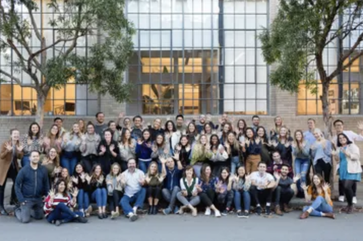 a group of people smiling and posing in front of a modern building