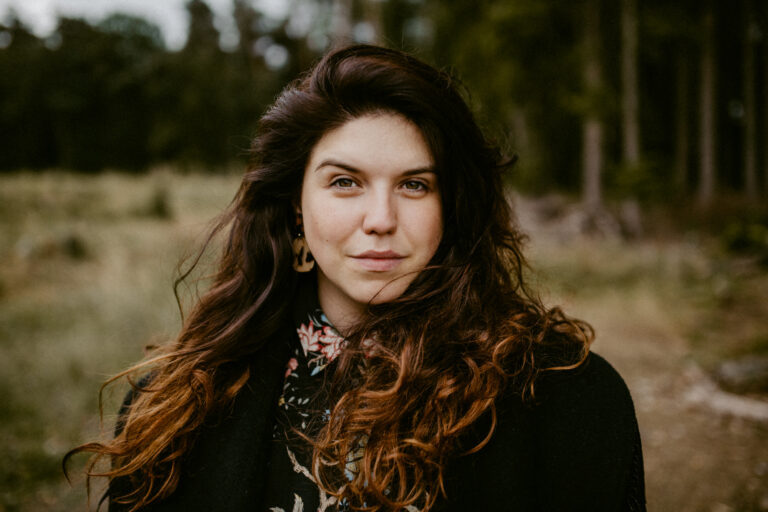 A headshot of a woman standing outside.