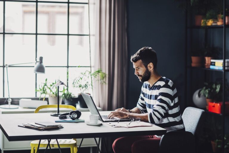 Man in a striped shirt working on a laptop.