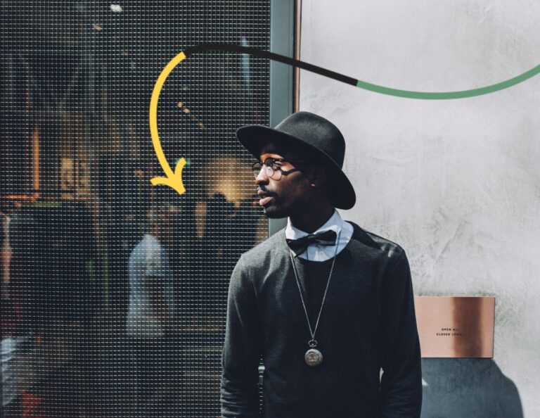 Stylish black man stands in front of department store looking to his right.