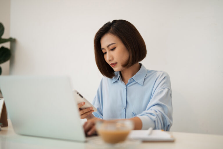 a woman with a laptop and phone learning how to discover her leadership style