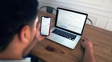 person looking at finance dashboards on their phone and computer