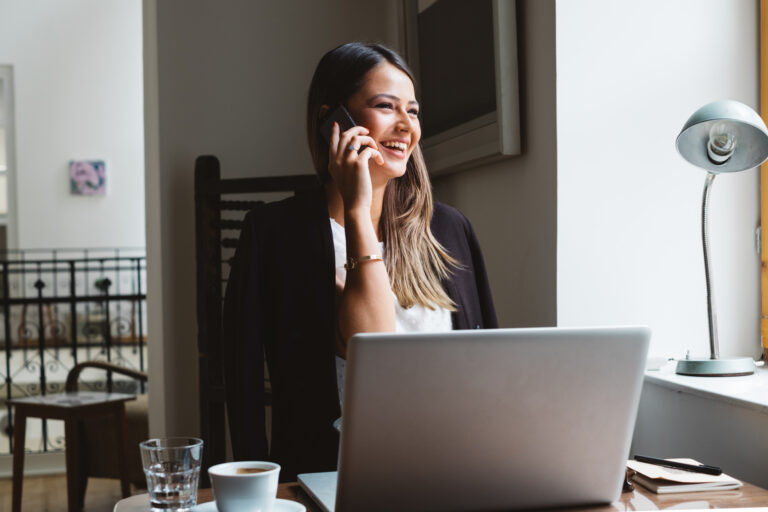 Businesswoman Talks On A Phone While Working On Laptop