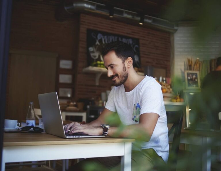 Man sitting in coffee shop at a table using his laptop