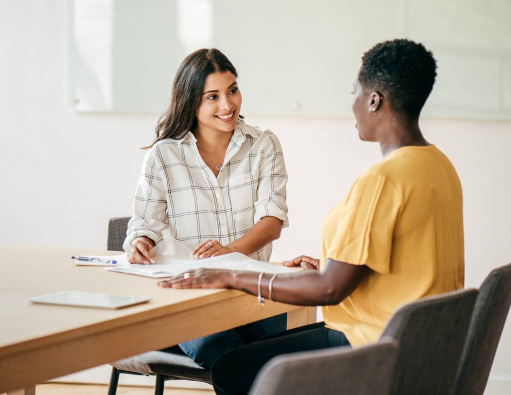 Woman business owner asking client background questions to another woman as they're seated