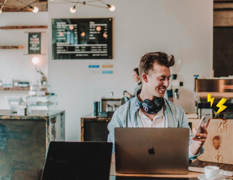 Man uses his phone and computer in a cafe.