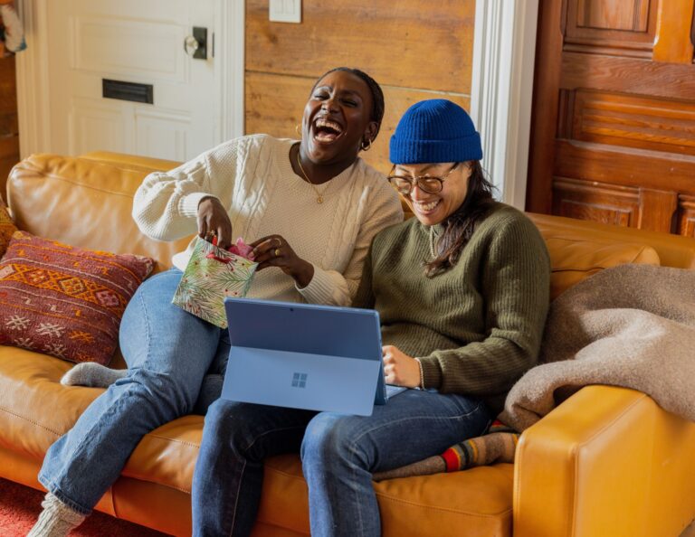 Two marketers laugh at something on a computer.