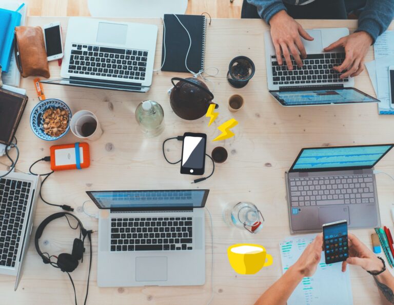 Friends gather around a table with their tech devices.